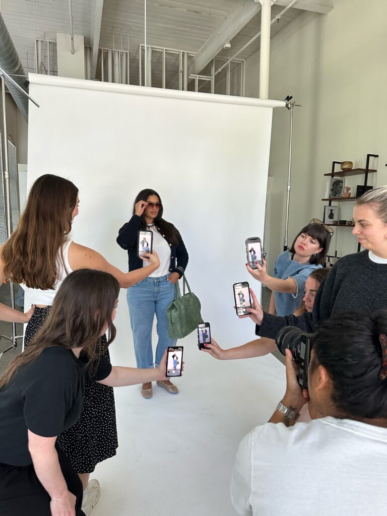 A group of women taking photos of another woman in a content photo shoot
